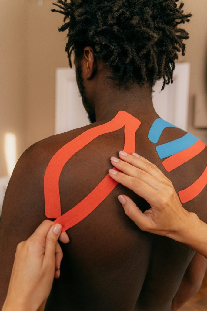 A Person Putting Kinesio Tape on Man's Back